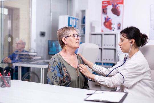Female physician listens to the upper chest of an older patient with a stethoscope in a clinic, combining physical examination with attentive senior care, highlighting patient care.