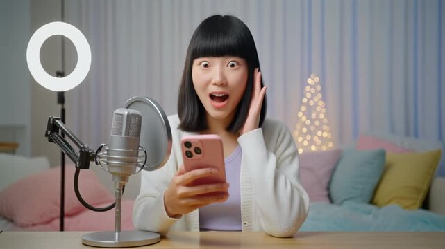 明るい配信ルームでスマートフォンを見て驚きの声を上げる若い女性