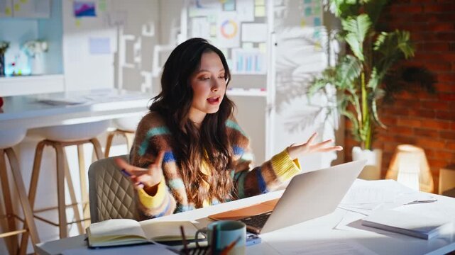 Asian freelancer gesturing video call home office. Expressive online meeting.
