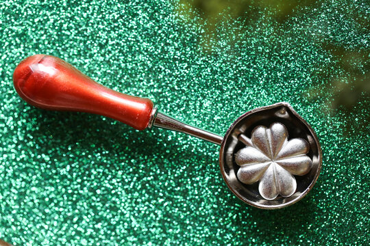 Metal Clover Molds on Glittering Green Background. Happy New Year Silver Lucky in Tin Pouring Spoons . traditional holiday prediction game for family celebrations