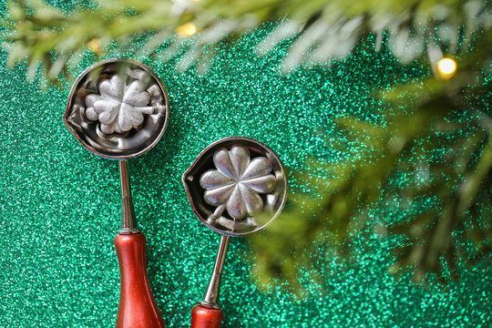 Happy New Year Silver Lucky in Tin Pouring Spoons on green glitter. traditional holiday prediction game for family celebrations,holiday greetings,fortune telling traditions,party invitations 
