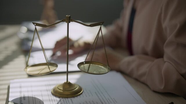 Justice scales in sharp focus with a lawyer reviewing documents in the background, representing legal research, contract review, case analysis, professional consultation, rights, and law practice.