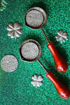 Tin Pouring Set on Green Glitter Background for tin pouring instructions,holiday gift sets and New Year fortune telling activities.New Year Tin Pouring Set with Green Glitter Copy Space. 