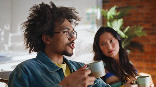 Multiethnic friends coffee break brick loft. Close up man drinking tea talking.