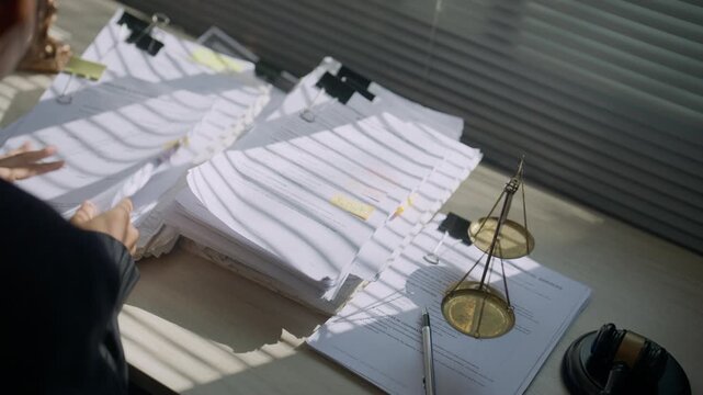 Close-up of balanced justice scales with a professional working in the background, symbolizing fairness, equality, legal ethics, judicial decisions, civil rights, authority, and rule of law.