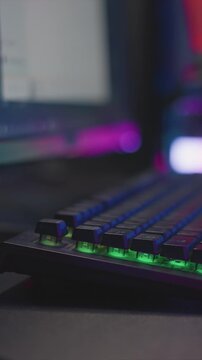 Close up view of mechanical keyboard with RGB backlighting focusing on keys and hand movements. scene features vibrant green lighting under keycaps while fingers press down on person buttons