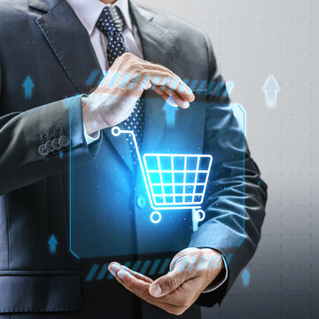 Businessman holding a glowing digital shopping cart icon with blue futuristic elements, symbolizing digital marketing, and retail technology. Concept of Online shopping, E-commerce and Modern Retail