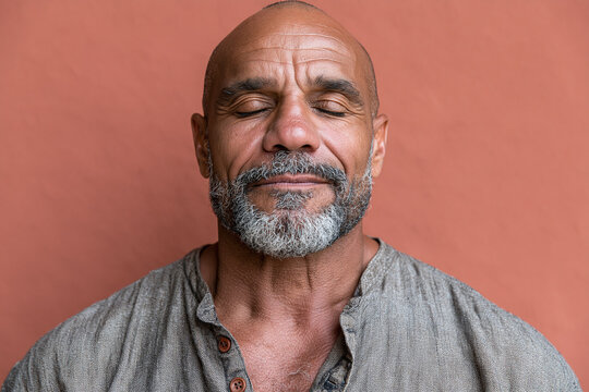 Closed eyes portrait of mature man with salt and pepper beard, relaxed expression, linen shirt, textured background
