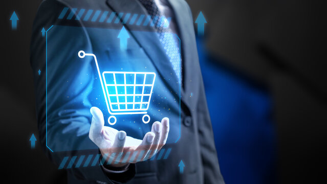 Businessman holding a glowing digital shopping cart icon with blue futuristic elements, symbolizing digital marketing, and retail technology. Concept of Online shopping, E-commerce and Modern Retail