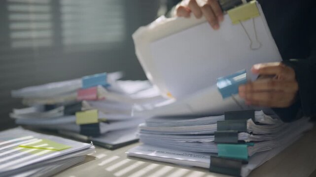Legal worker examining documents from stacked case files, representing evidence review, investigation, legal research, litigation strategy, case preparation, documentation, and judicial procedures.