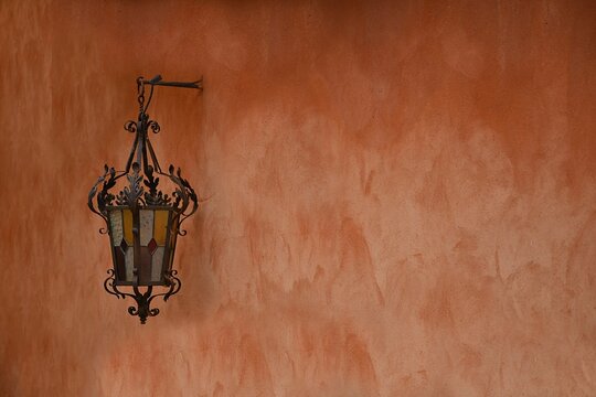 Handmade stained glass Medieval style antique lantern on a Venetian red ochre stucco wall in Roussillon, Vaucluse Provence, France.