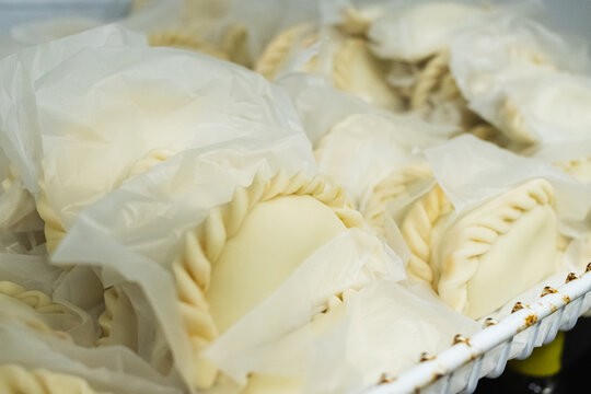Uncooked raw empanadas wrapped in parchment paper separator sheets prepared for cooking or freezing
