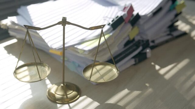 Scales of justice displayed beside stacked legal documents and files in an office, representing law, court cases, legal research, documentation, litigation, justice, and professional legal work.
