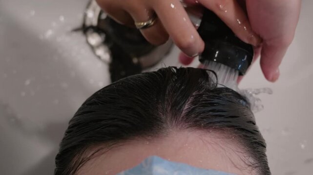 Hairdresser rinsing shampoo from hair at a salon basin