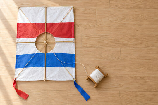 Korean shield kite with bamboo frame and string spool on wooden floor