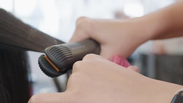 Hairdresser straightening sectioned hair with a flat iron