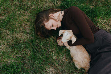 Obraz premium woman, goat, kid, lifestyle, outdoor, nature, bonding, relaxation. A calm woman lies on green grass, cuddling a gentle goat kid in a peaceful yard, with soft light creating a warm, wholesome mood.