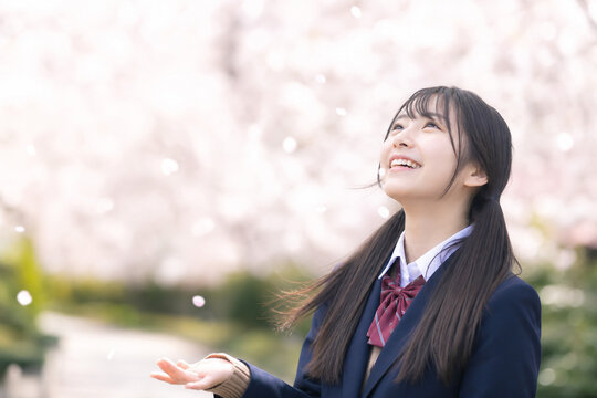 満開の桜を見上げて笑顔を見せる日本人女子高校生