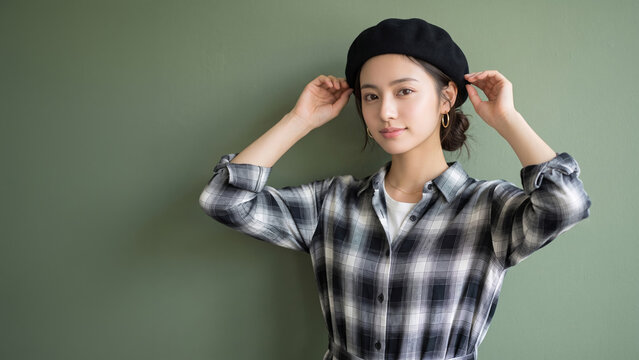 黒いベレー帽をかぶりチェックのシャツを着てカメラを見つめる女性