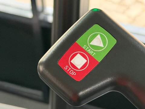 Close up fitness machine handlebar with green start button triangle icon and red stop button square icon, workout routine and gym safety
