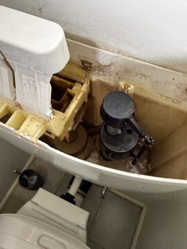 Inside a toilet cistern showing the fill valve, float and flush mechanism with limescale stains