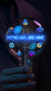 Businessman hand holding glowing lightbulb vertical shot with knowledge text and innovation icons. Intellectual capital management, corporate learning development, and visionary thinking concept.
