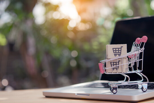 Shopping online. Cardboard box with a shopping cart logo in a trolley on laptop keyboard. Shopping service on The online web. offers home delivery