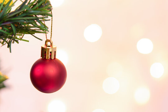 Red christmas tree ornament bauble decoration hanging on pine branch creates joyful festive holiday background with soft light bokeh for merry season card
