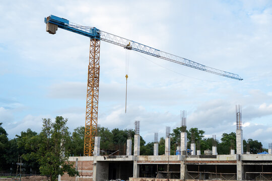Tall crane operates at active construction site, lifting heavy machinery equipment and steel structure for new building tower with ambitious architectural vision
