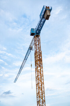 Tall construction tower crane standing high against blue sky shows ambitious engineering strength in heavy equipment industry with proud tall structure