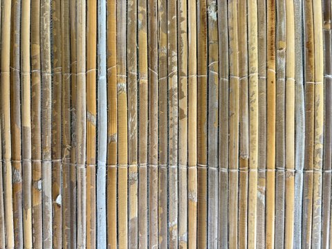 Close-up detail of a traditional vertical bamboo woven mat or screen, showcasing natural textures and organic patterns.