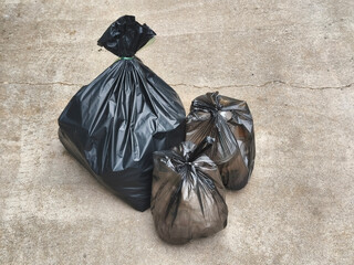 Three Black Plastic Garbage Bags on Concrete © thekopmylife