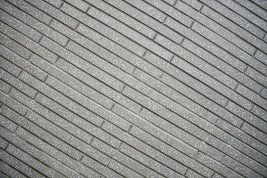 Diagonal view of grey granite effect tile wall with grooves background