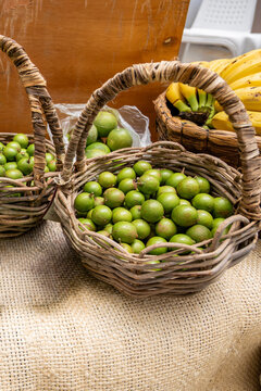 Fresh tropical guineps, spanish limes, or mamoncillo fruits filling rustic wicker baskets at a market stall, ready for healthy eating and snacking
