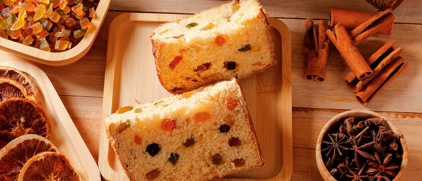 Traditional Christmas panettone sliced with candied fruit and spices on a wooden table.