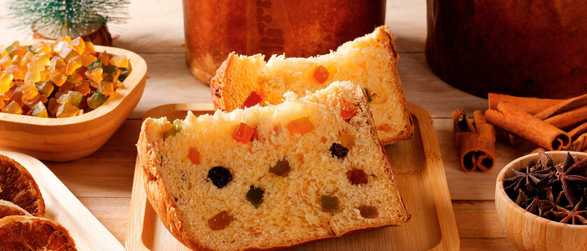 Traditional slice Christmas panettone with candied fruit and spices on rustic wooden table.