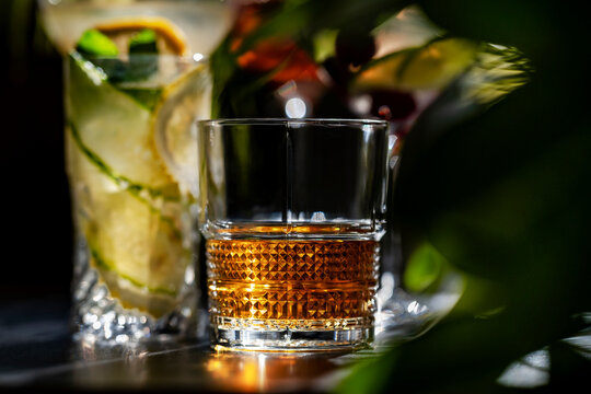 Hard spirit cocktail in glass &mdash; traditional strong alcoholic beverage. Luxury nightlife and evening recreation. Golden bourbon or scotch whiskey over ice serving as classic warming drink for adults.