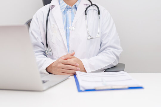 Professional doctor wearing lab coat using laptop and taking report notes on notebook for November Lung Cancer Awareness month, World Cancer Day and oncology healthcare concept in hospital