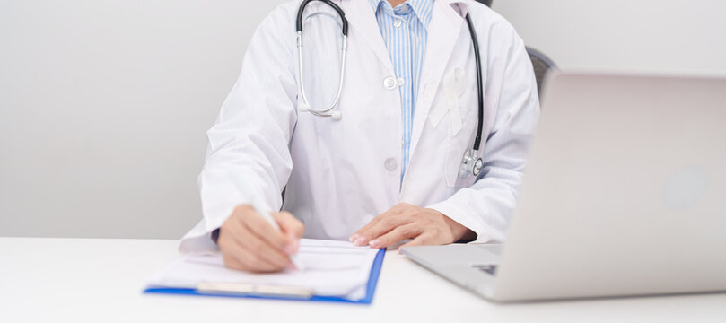 Professional doctor wearing lab coat using laptop and taking report notes on notebook for November Lung Cancer Awareness month, World Cancer Day and oncology healthcare concept in hospital