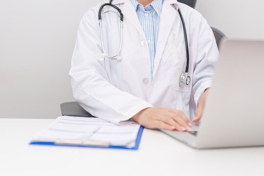 Professional doctor wearing lab coat using laptop and taking report notes on notebook for November Lung Cancer Awareness month, World Cancer Day and oncology healthcare concept in hospital