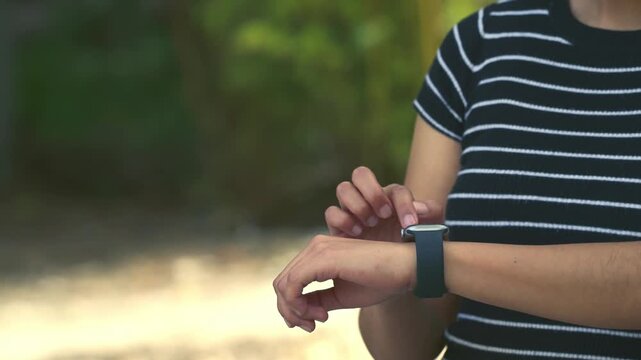 Woman using a smartwatch outdoors while wearing a striped t-shirt