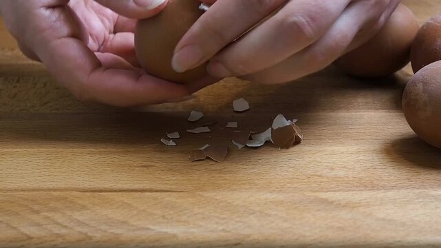 Female hands close-up clean boiled chicken egg. Home kitchen wooden table.