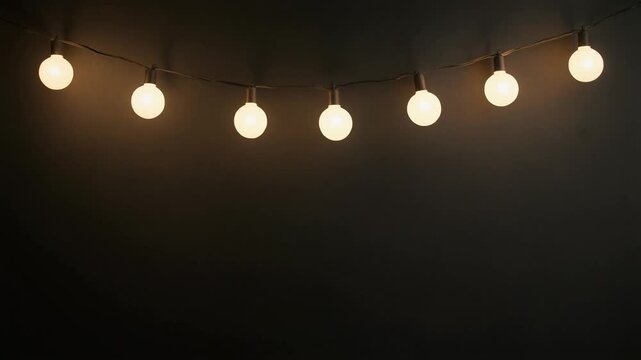 String lights with glowing warm white globe bulbs for party and holiday, dark background copy space