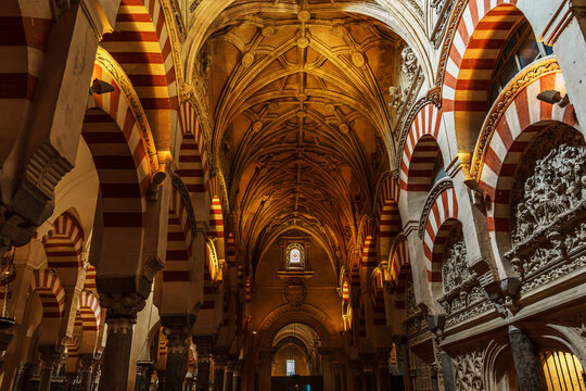 Gothic ribbed vault nave framed by red and white striped arches and stone reliefs in the Mezquita of Cordoba