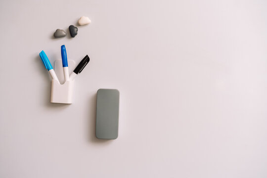 Blank whiteboard with three markers and an eraser below right and three small magnets.