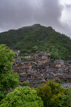 Misty mountain village of wooden houses on a forested slope, near Xijiang, Guizhou, China