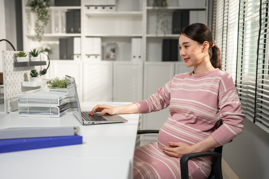 Asian young pregnant businesswoman working with happiness in the office. 