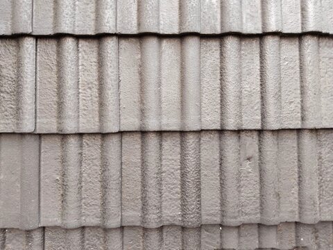 an arrangement of concrete roof tiles or cement roof tiles that have a vertical wave profile with a parallel and tiered stacking pattern horizontally installed neatly on the roof structure,