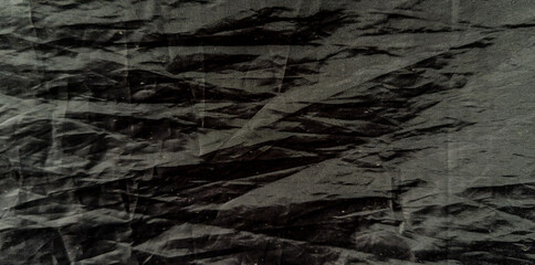 textured black fabric with intricate folds and creases, creating a visually striking pattern. Perfect for backgrounds, banners, or posters. © Alizar