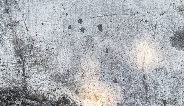 textured concrete surface with a worn, weathered appearance, featuring scratches, stains, and a mix of light and dark tones, ideal for backgrounds and design elements.